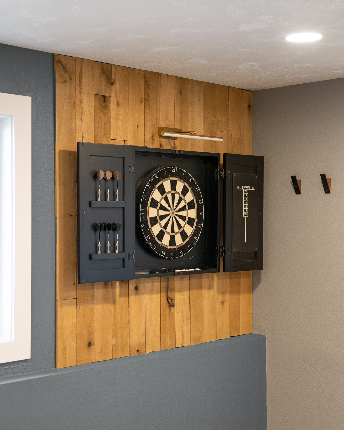 Dartboard cabinet on wood panel wall