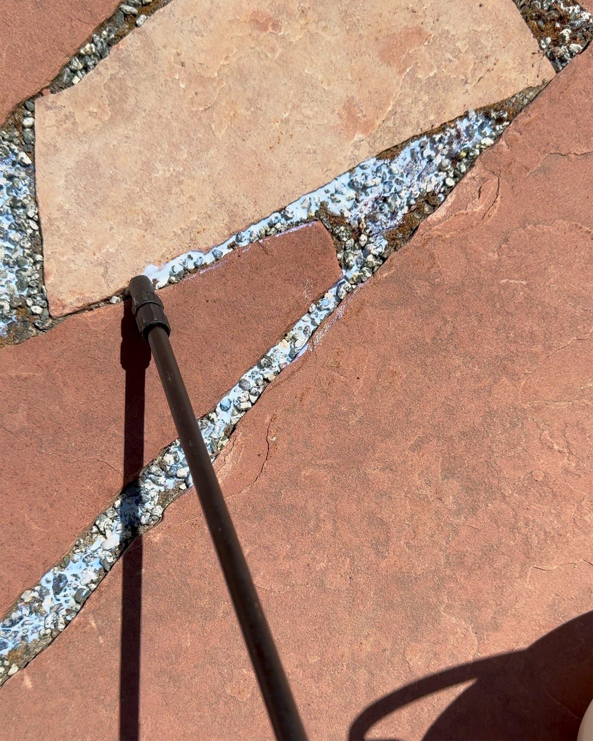 applying rock glue to pea gravel flagstone pathway with garden pump sprayer