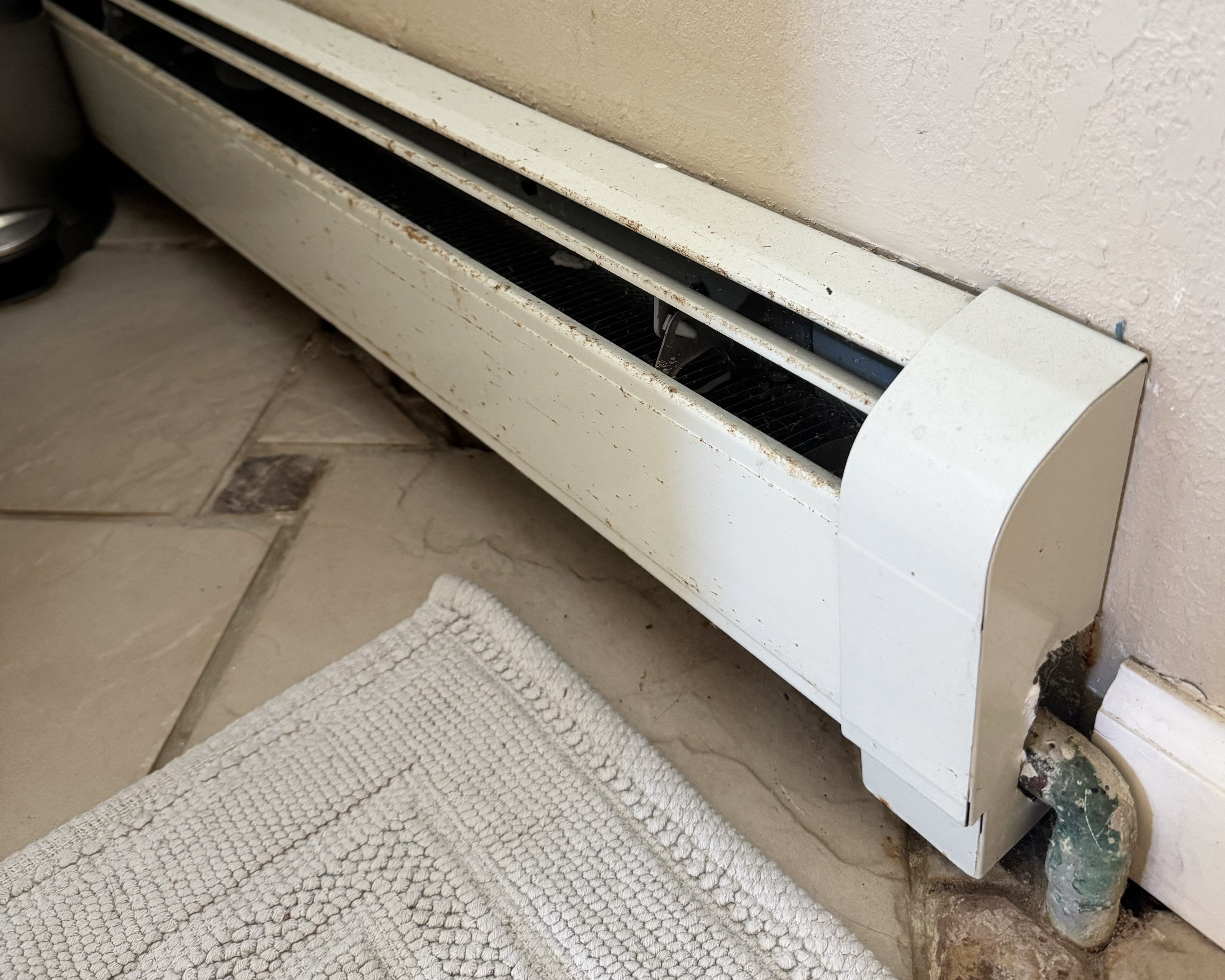 Old rusty baseboard heater in bathroom