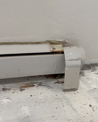 Old rusted and painted over baseboard heater in closet